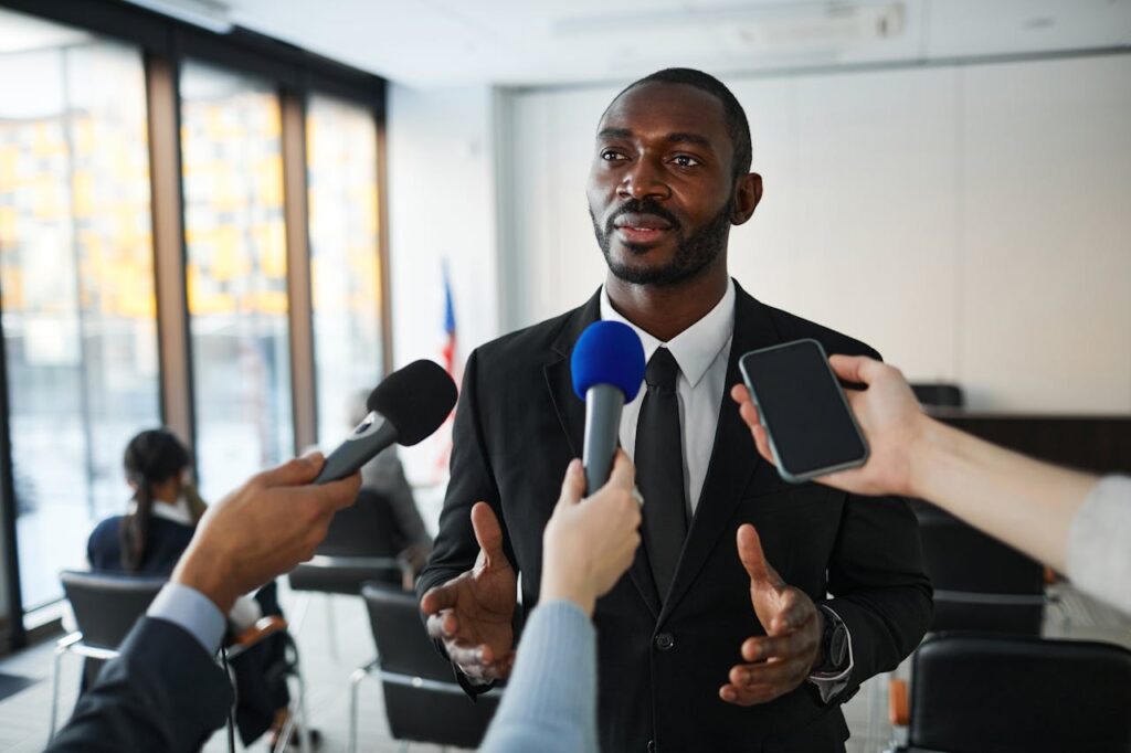 Confident businessman answering questions from the media during a press conference indoors.
